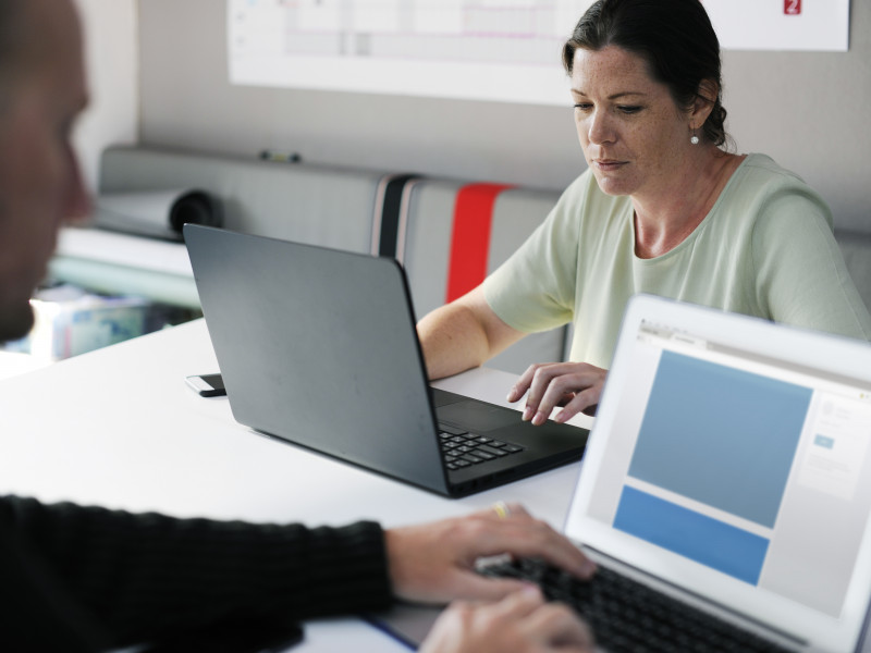 2 people working on laptops in an office space