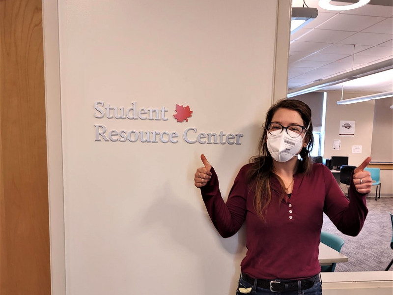 Woman next to student resource center sign