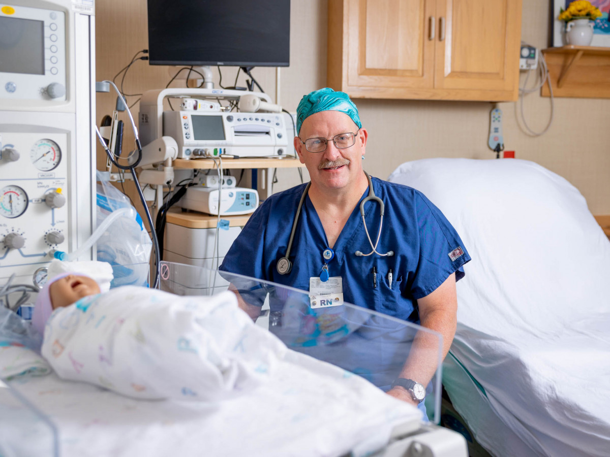 Scott Lamberti sitting in hospital room with baby in front of him